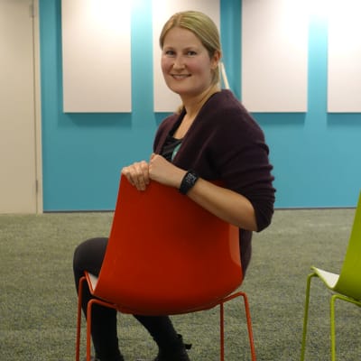 Foto på Katarina Rehnström som sitter på en färgrann stol i EHYTs kontor