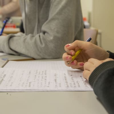 En elev skriver i sitt häfte i en skolklass.