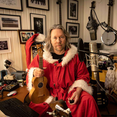 Kuopion yliopistollisen sairaalan ylilääkäri Tatu Kemppainen joulupukiksi pukeutuneena kitara kädessä.