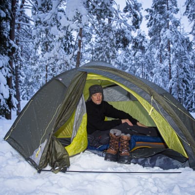 Mies majoittuu teltassa talvella. 