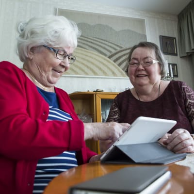 Kaksi mummoa käyttää tablettia kotona