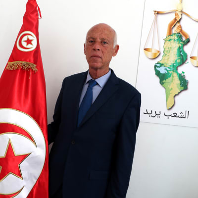 Bild på man som står vid tunisiens flagga.