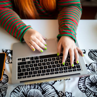 Studerandes händer som skriver på en bärbar dator.
