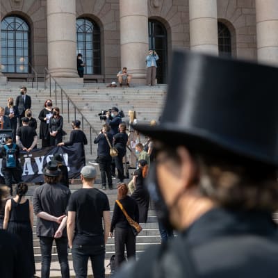 Människor klädda i svart utanför riksdagshuset i samband med en demonstration.