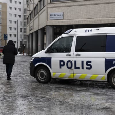 En polisbil utanför Böles polishus 1. Bredvid den går en fotgängare på en isig trottoar.