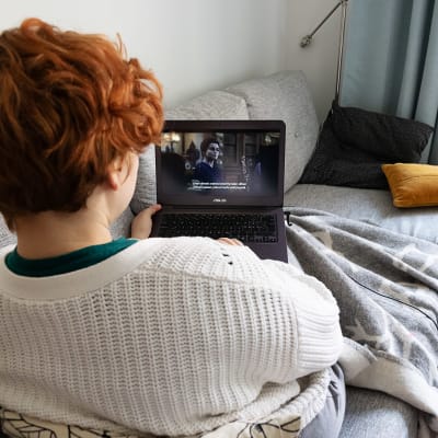 En person tittar på Netflix på soffan, via en bärbar dator.