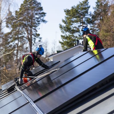 Solarvoima Oy:n asentajat Joni Särkinen ja Erik Aho asentavat  aurinkopaneeleja omakotitalon katolle.