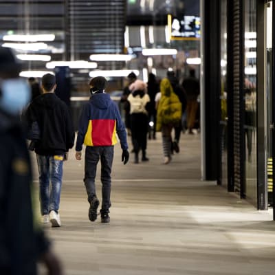 Flera mörkklädda ungdomar hänger ihop i ett köpcentrum.