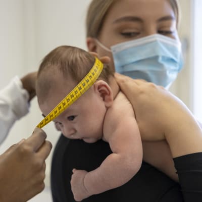 Terveydenhoitaja mittaa vauvan päänympärystä.