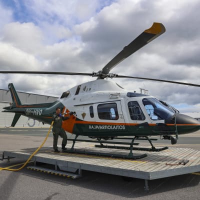 Rajavartiolaitoksen lentomekaanikko tankkaa helikopteria ennen valvontalennolle lähtöä.