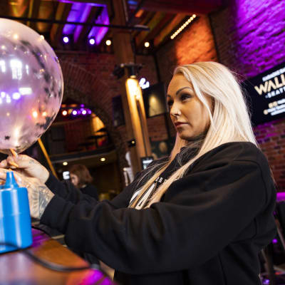 Ravintolapäällikkö Malla Rosenius täyttää ilmapalloa karaoke bar Walliksessa.