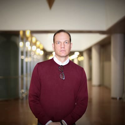 Robin Harms, specialsakkunnig vid diskrimineringsombudsmannens byrå, i vinröd tröja i en korridor.