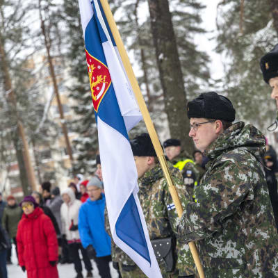 Karjalan lennoston varusmiehiä ja henkilökuntaa seisoo suomen valtion lipun vieressä