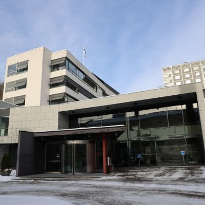 Åbo rättscenter, en vit byggnad med stora fönster, fotograferat en solig vinterdag med snö på marken.