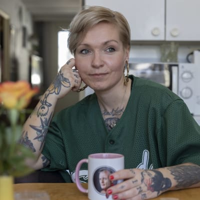 Mira sitter vid köksbordet. Hon är glad, har rosor på bordet.