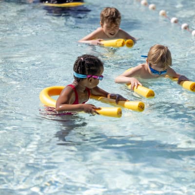 Barn med simkuddar i en simbassäng. 