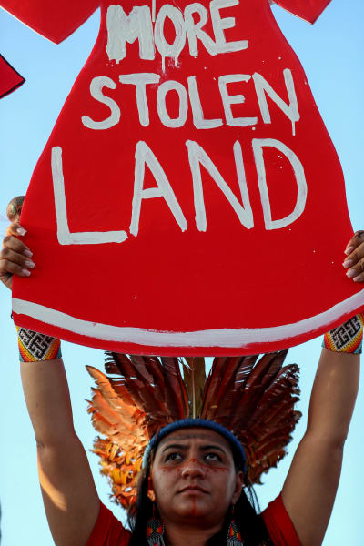 Demonstrant från ursprungsbefolkning håller upp skylt med texten No more stolen land, Sluta stjäla vårt land