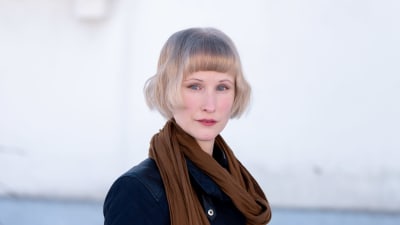 Kirjailija Iida Rauma vaalean rapatun talon edessä.