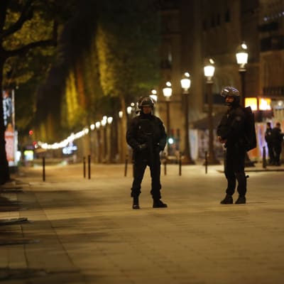 Två tungt utrustade poliser står på en ödslig gata i Paris, efter skottlossningen på Champs-Elysées.