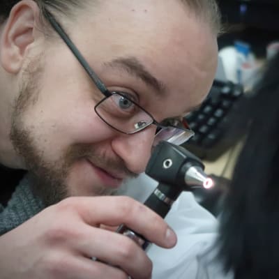 Terveyskeskuslääkäri Joonas Joensuu tutkii potlasta valon kanssa.