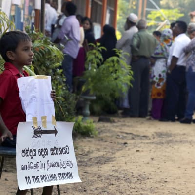 En pojke väntar på sina föräldrar, som röstar i Sri Lanka.