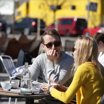 Vänner dricker kaffe ute på terrass.