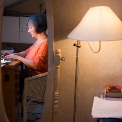 Henkilö kirjoittaa tietokoneella työpöydän ääressä.
