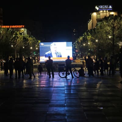 Människor följer med tv-rapporteringen från parlamentsvalet på Skanderbegplatsen i Tirana.