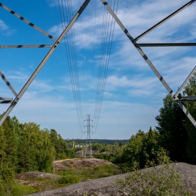 Sähkölinja kulkee metsän läpi, kallion yli kaukaisuuteen.