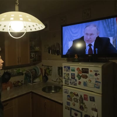Henkilö kuuntelee, kun Vladimir Putin puhuu televisiossa.