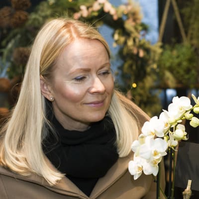 Susanne tittar på vita orkidéer i en blomaffär.