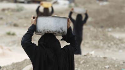 Kvinna i Jemen transporterar vattenkärl
