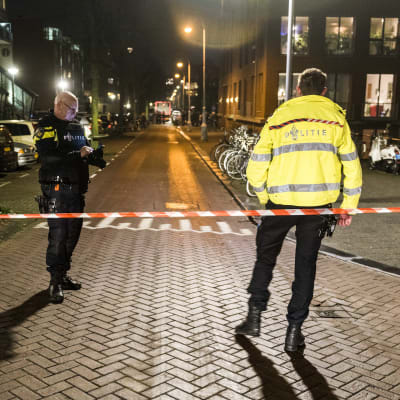 Två poliser står bakom avspärrat området efter skottdrama i Amsterdam.