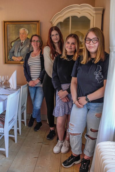 Fyra unga kvinnor poserar vid ett hörnskåp i en restaurang.