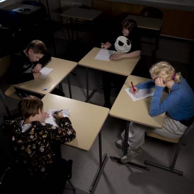 Fyra elever sitter med pulpeterna hörn-i-hörn och skriver för hand.  
