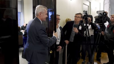 Journalister på sin vakt då Pekka Haavisto öppnar dörren till grundlagsutkottets mötesrum.