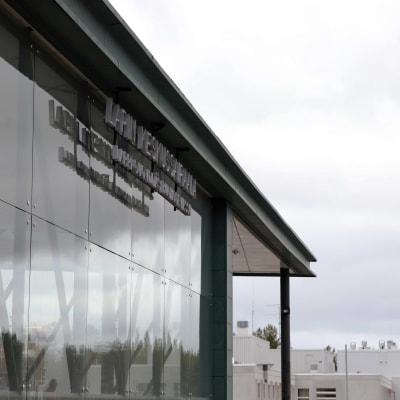 Lapin Keskussairaalan lasinen seinärakennelma ja kyltti, sekä pivistä taivasta.