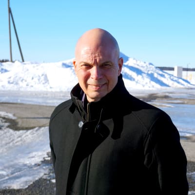 Man i svart rock står i en hamn.