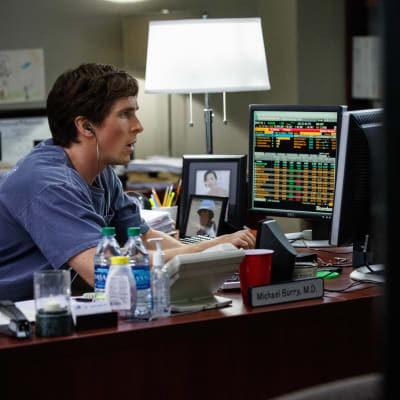 Christian Bale sitter vid datorskärmar och undersöker börskurserna.