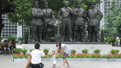 Familj poserar framför statyer i Kina.