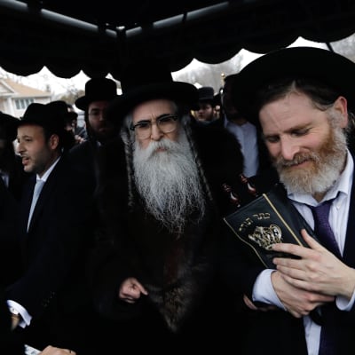 Juutalaiset kokoontuivat seremoniaan rabbi Chaim Rottenbergin kodin edustalle 29. joulukuuta. Päivää aiemmin taloon tunkeutunut mies puukotti viittä ihmistä.