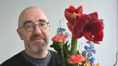 Äldre man håller i blombukett
