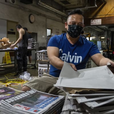 Työntekijät niputtavat Apple Daily -lehden numeroita.