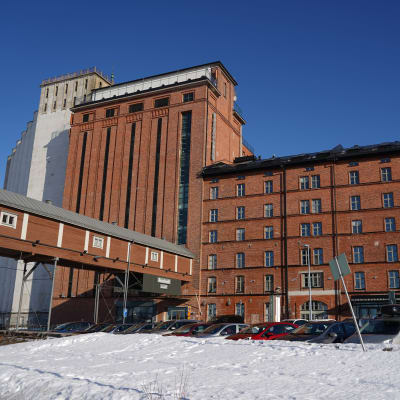 Åbo Akademi i Vasa. En stor gammal fabriksbyggnad i tegel reser sig mot en blå himmel.