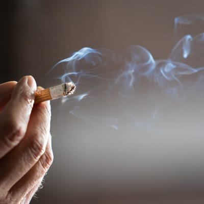 En närbild av en hand som håller i en cigarett. 