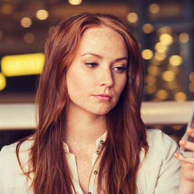 Kvinna tittar fundersamt på sin smarttelefon
