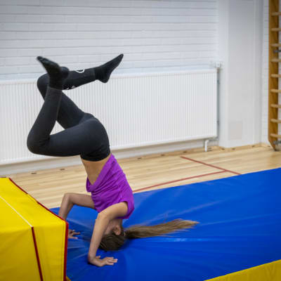 Tyttö tekee parkourtemppua koulun liikuntasalissa. 