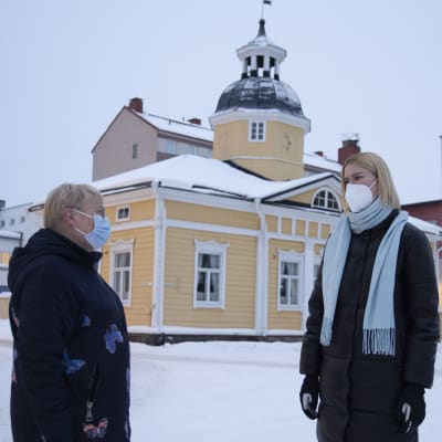 Kaksi naista seisovat lumisella aukiolla vastakkain katsoen toisiaan.