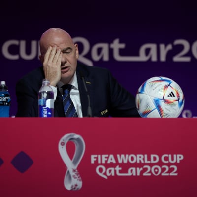 Fifan puheenjohtaja Gianni Infantino istuu lehdistötilaisuudessa ja hieroo oikealla kädellään kasvojaan. 