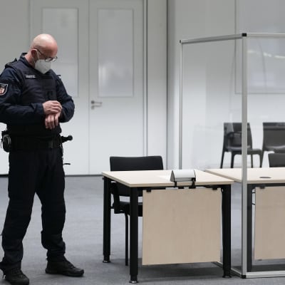 En polis i uniform står och tittar på sin klocka inför en rättegång. 